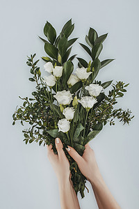 女性手捧花束的裁剪图像灰色洋花