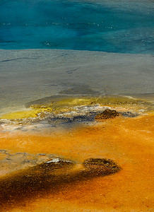 温泉中的金硫磺残留物，后面是蓝色的水