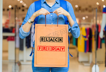 特写妇女藏品购物袋在购物中心与黑色星期五词概念.