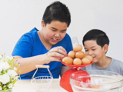 愉快地摄影照片_孩子们愉快地称着准备做蛋糕的生鸡蛋.