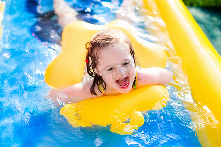 水飞溅摄影照片_在充气花园游泳池玩耍的小女孩