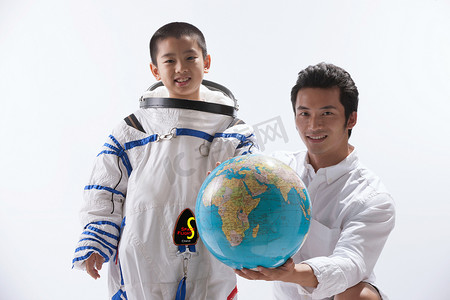 儿童宇宙摄影照片_穿宇航服的小男孩和青年男人拿着地球