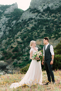 令人惊叹的新郎新娘拥抱对方温柔站在金色的山上