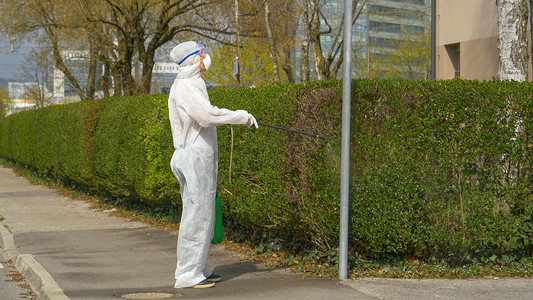 Virologist disinfects a street lamp and sidewalk during covid-19 outbreak.