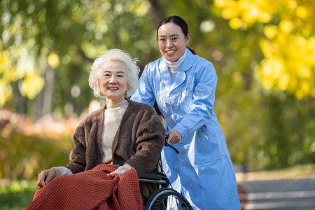 医生交谈摄影照片_护士推着坐在轮椅上的老人散步