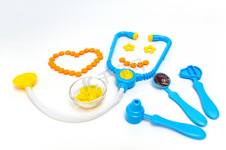 Blue stethoscope, otoscope, hammer, dental mirror Isolated on white background. Medicine concept. Childrens toys by profession doctor. A heart is by orange pills. Stethoscope smiles.