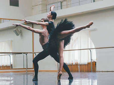 年轻的男子在古典芭蕾与年轻漂亮的女子在健身房的黑色芭蕾舞短裙的服装练习。简约的内饰, 舞蹈性感的舞蹈.