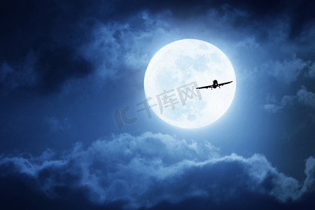 戏剧性的夜间天空大蓝色满月与商用飞机