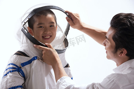 儿童理想摄影照片_青年男人给小男孩穿宇航服
