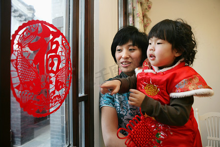 剪紙窗花摄影照片_中国年轻妈妈抱着孩子