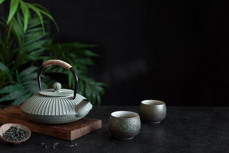 茶壶背景摄影照片_在黑色背景上的茶壶和茶杯, 复制空间。传统的亚洲安排茶道-铁茶和陶瓷茶杯与茶.