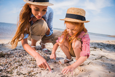 海滩捡贝壳摄影照片_母亲和女儿捡贝壳