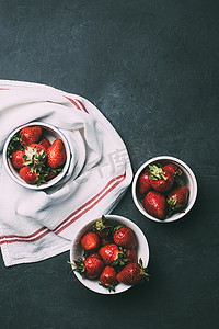 红草莓摄影照片_红色的碗和毛巾的成熟红草莓的顶部视图 