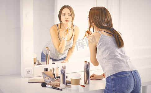 惊人的年轻女子做她的化妆在镜子前。波尔特拉