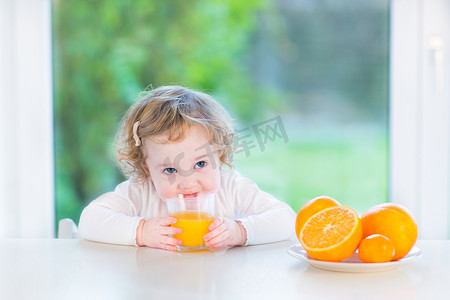 可爱的小孩女孩喝桔子汁坐