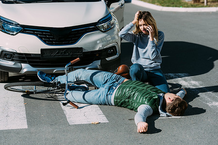 车祸发生后, 年轻女子紧急拨打电话, 看着躺在路上的受伤骑自行车的人 