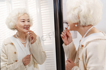 时尚的老年女人对着镜子化口红