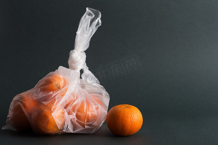 Fruits in plastic bags on a dark background. Image shows the harm of using artificial food storage bags