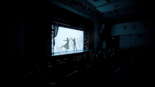 在舞台上，年轻男女在传统芭蕾中练习的轮廓。视频。黑暗的音乐厅，观众在看芭蕾舞.