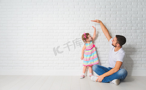 概念。爸爸措施生长的女儿的孩子在一堵墙