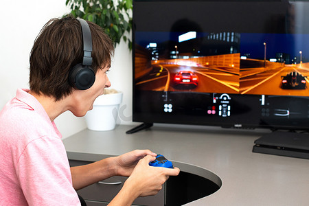 游戏ppt摄影照片_青少年男孩在网上玩一个带耳机和操纵杆的电脑游戏，游戏主机.