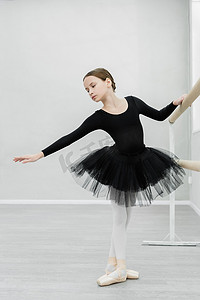 穿着黑色芭蕾服装在舞厅接受训练的优雅女子全景