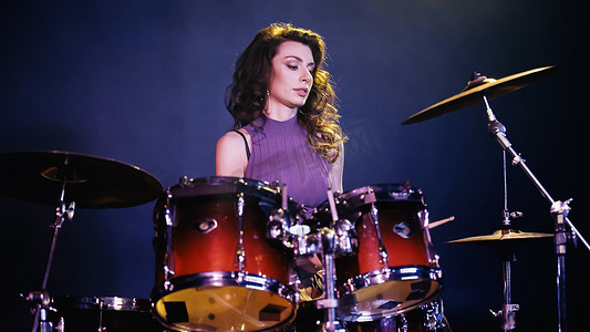 pretty drummer playing on drums during performance on stage