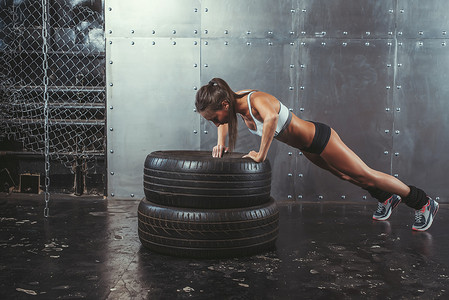 女运动员。合适的运动型女人做推轮胎强度力量训练概念运动量来找到健身锻炼运动和生活方式的 ups.