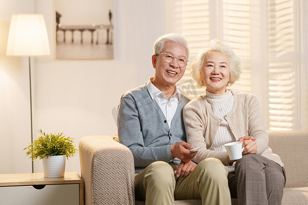 关爱老年健康摄影照片_幸福的老年夫妇坐在沙发上看电视