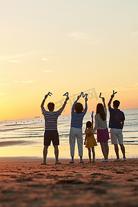 海边夕阳天空摄影照片_在海边度假的快乐家庭