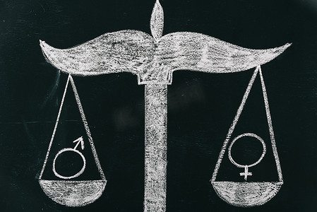 在黑板上的鳞片上的男性和女性标志, 性别平等概念