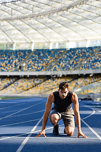 英俊潇洒的赛跑选手在体育场跑道上的起跑位置