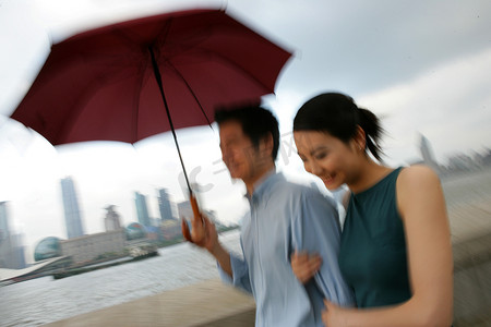 外滩黄浦江边一对情侣同撑一把伞行走