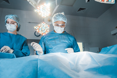 护士和外科医生在制服和医疗口罩做手术 