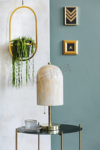现代组合的客厅室内设计咖啡桌，大理石台灯，挂花坛，植物和优雅的配件。现代家居装饰。模板。黄金模拟相框.