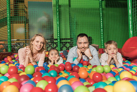 愉快的家庭微笑在照相机, 当说谎在水池与五颜六色的球  