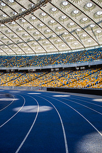 奥运体育场空荡荡的蓝色跑道，背靠着空看台
