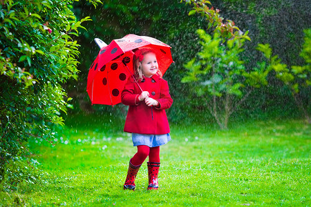 雨中儿童摄影照片_Little girl with umbrella playing in the rain