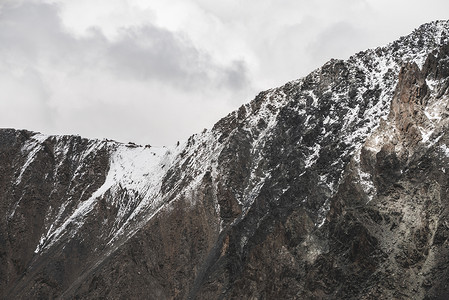 大气极简主义高山景观与雪山山峰。巨大雪域之上的低云.巨大的岩石与雪。巨大而崎岖的山脊。高空壮丽的风景.