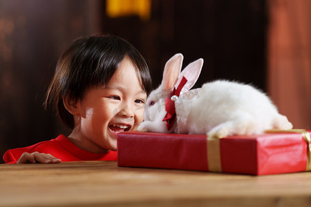 可爱的小男孩趴在桌子上观察小白兔