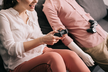 女性与假人在附近玩视频游戏在家里, 孤独的概念裁剪拍摄