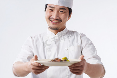 中国菜摄影照片_穿着厨师服的中年男人端着美味佳肴