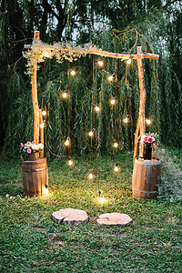 订婚仪式, 爱, 设计理念。在暮色中, 有令人惊叹的婚礼拱门, 装饰着质朴的风格, 闪耀着灯光, 花束着各种鲜花