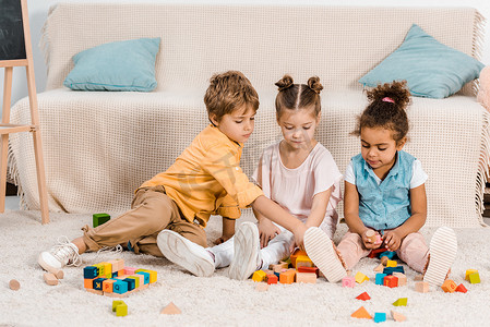 孩子在玩摄影照片_可爱的小民族孩子在地毯上玩五颜六色的立方体