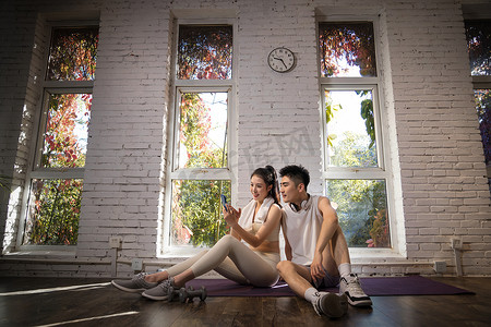 健康瘦身摄影照片_健身完的青年夫妇坐在地上休息