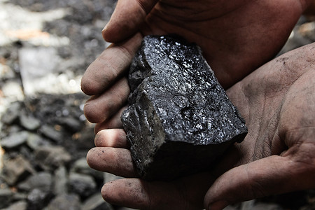 煤矿矿工在人手中的煤炭背景。煤炭开采或能源、环保。工业煤。火山岩.