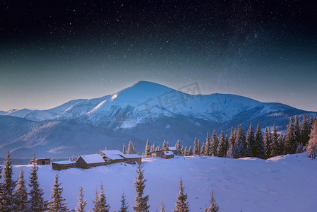 喀尔巴阡山村的月亮升起了，山上有木制的房子，覆盖着新雪。在繁星点点的天空中，这是一种神奇的银河般的方式。圣诞冬夜.