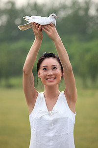 东方女人在户外手捧和平鸽