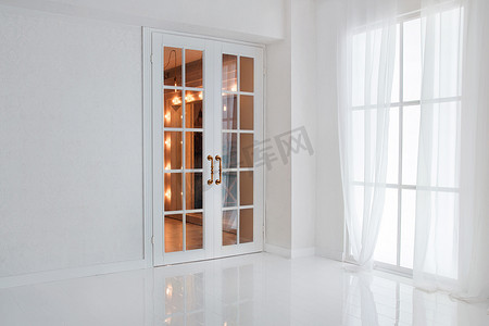空白色房间与大窗口和玻璃法国门与明亮的橙色光