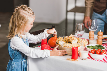 感恩节banner摄影照片_感恩节，可爱的女儿拿着盛有玉米和南瓜的碗 